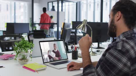 hombre de oriente medio teniendo una videollamada con un colega masculino en una computadora portátil en la oficina