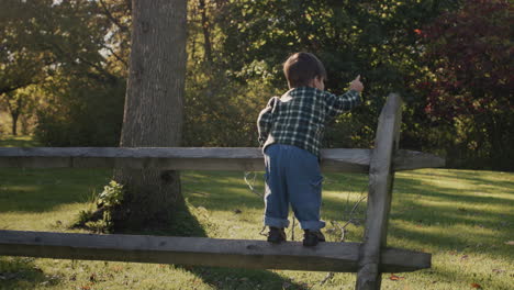 Happy-Asian-toddler-running-along-farm-fence.-Handheld-shot