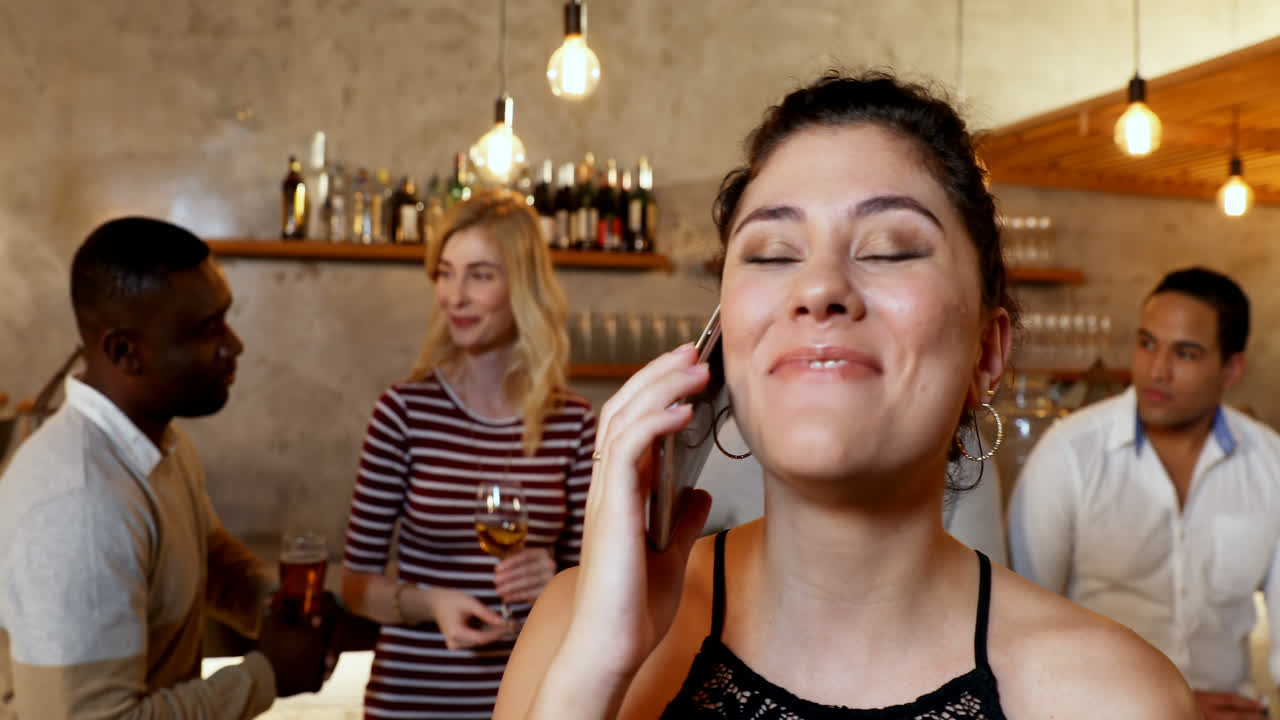 Giovane donna sorridente che parla al telefono mentre gli amici sono sullo sfondo 4K