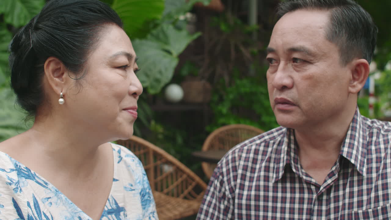 Mature Woman Listening to Husband Telling Sad Story in Cafe