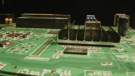 beautiful macro of a circuit board filled with a variety of components in a dark studio. the camera moves closely over the printed board