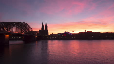 fire red cloudy, colorful timelapse with cologne cathedral and hohenzollernbridge and rhine river in the foreground. ships are passing.