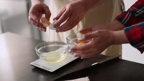 man and woman separating egg whites from yolk into bowl