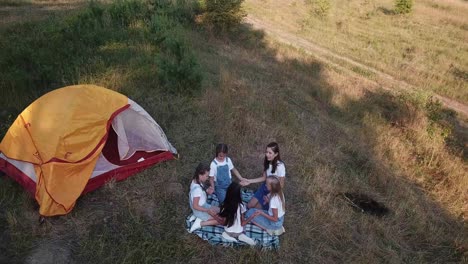 girls camping and playing on a grassy hillside