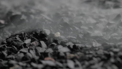 Extremely-Detailed-Close-up-Macro-Shot-Of-White-Mist-Covering-Black-Stones