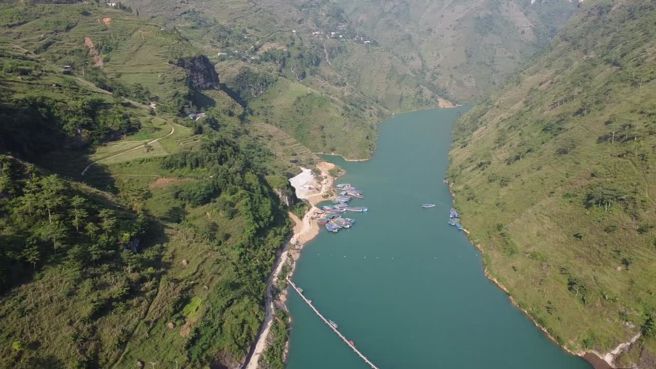 Drone video captures breathtaking aerial footage of a tranquil river winding through lush, green Vietnamese valleys under clear blue skies, showcasing stunning natural beauty