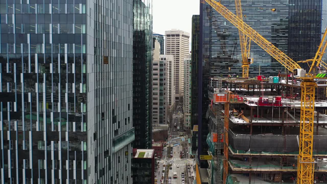 vista aérea entre rascacielos en seattle con grúas trabajando en un sitio de construcción