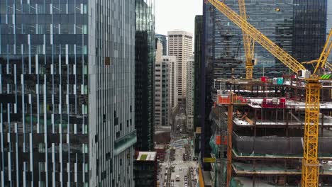 aerial view between skyscrapers in seattle with cranes working on a construction site