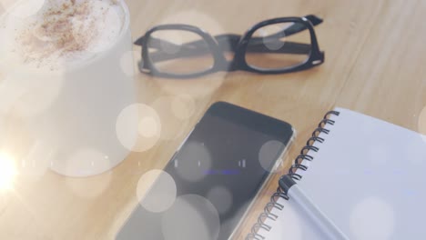 Animation-of-white-light-spots-over-notebook-and-smartphone-on-desk