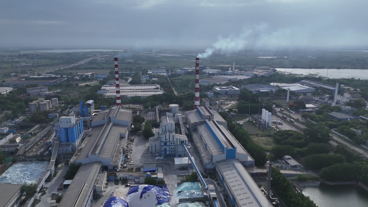 tomada aérea de una industria que libera gas contaminante cerca de un lago