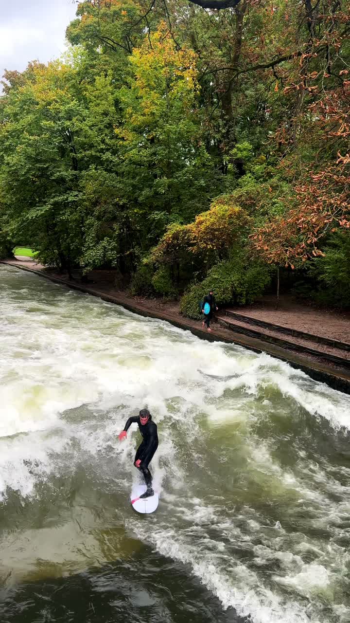 Våddragt-surfere River Surfing morgen Eisbachwelle Eisbach Isar River München Tyskland lodret turistattraktion broudsigt Efterår Englischer Garten stående bølge vand action sports stunts pan
