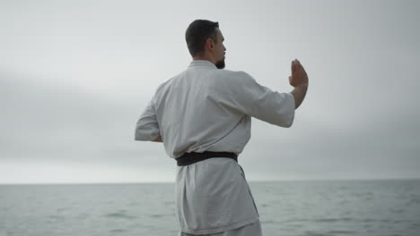 sportsman practicing hand position training karate near sea. man learn technique