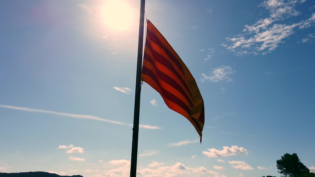 bandera catalana al sol con un cielo azul y algunas nubes