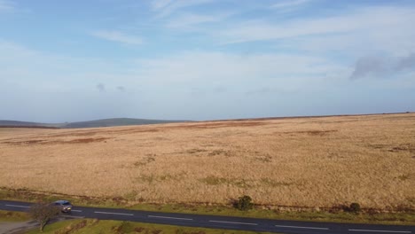 Rising-Aerial-Drone-Over-Countryside-Road-Revealing-Moorland-and-Rolling-Farmed-Fields-in-Exmoor-UK-4K