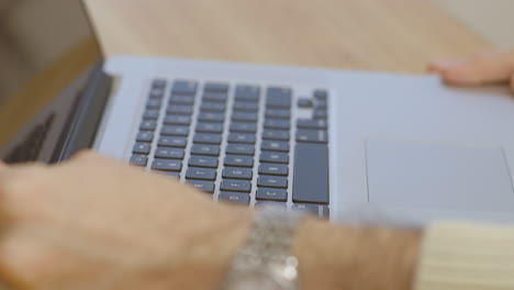 un primer plano de las manos de un hombre mientras saca una computadora portátil, comienza a escribir y luego la guarda