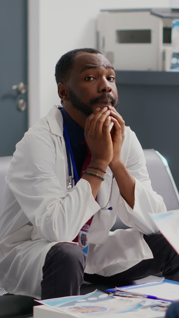 Vertical video: Stressed general practitioner sitting in waiting area lobby