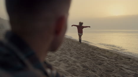 Pareja-Joven-Pasando-Vacaciones-En-La-Playa-Al-Amanecer.-Hombre-Sentado-En-La-Orilla-Del-Océano