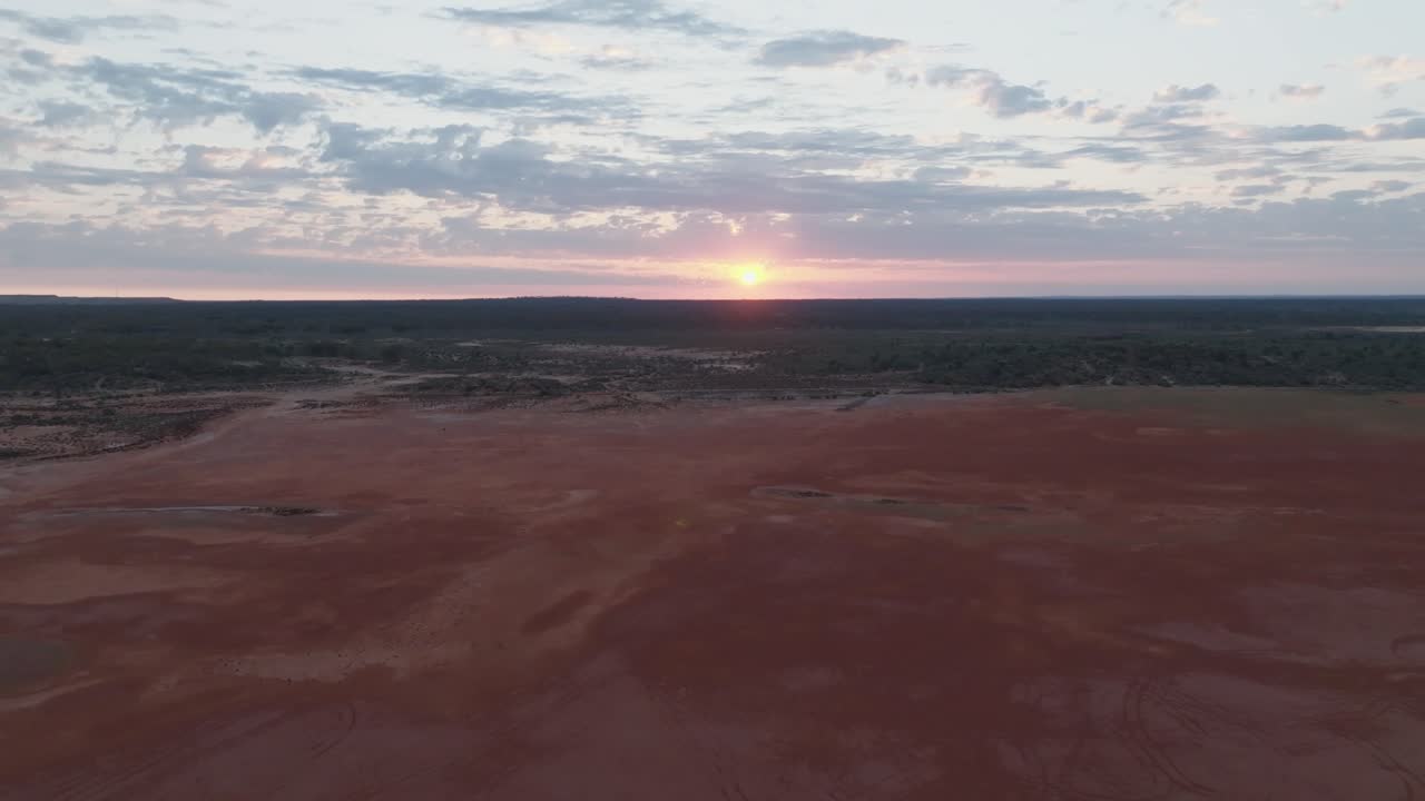 clip de dron que muestra el amanecer rosado a través de las nubes, sobre el colorido paisaje del interior de australia