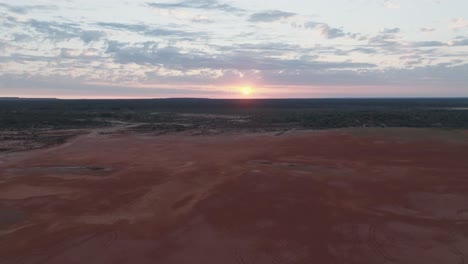 drone clip showing pink sunrise through clouds, over colourful australian outback landscape
