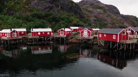 aerial low flying footage of the red rorbu houses in the beautiful fisher village of å in the lofoten islands, norway