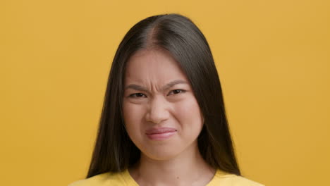young asian woman showing disgusted or unpleasant facial expression