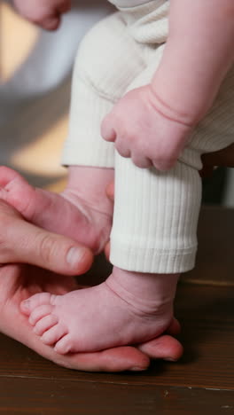 newborn baby feet stepping by the father's palm. happy newly-made parents and a family at home. close up. vertical video