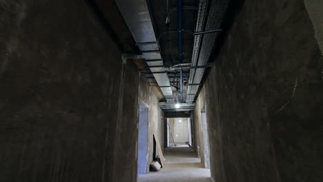 grey walls of the long corridor in the constructed building. low angle view at the pipes on the ceiling.