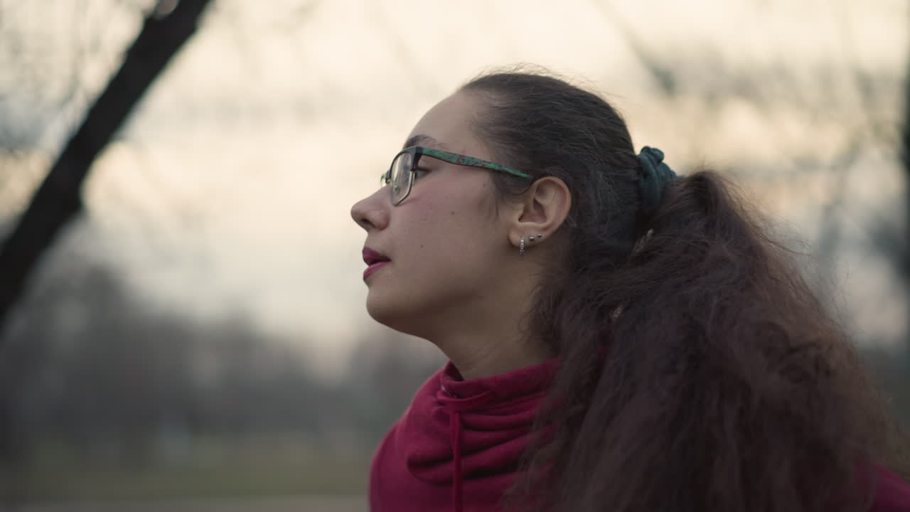 Young Woman Pauses After Running In Park Setting, Female Athlete Taking Break Following Outdoor Jogging Session, Young Woman Reflecting And Calming Down After Vigorous Park Run Session