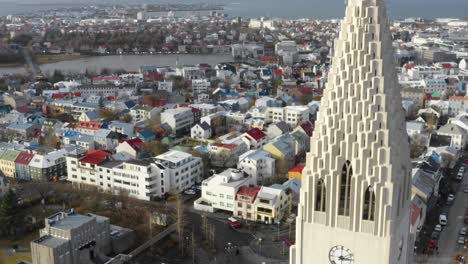 dron przelatuje obok hallgrimskirkja w katedrze w reykjavíku ze wspaniałą wieżą zegarową odsłaniającą za sobą kolorowe dachy miasta