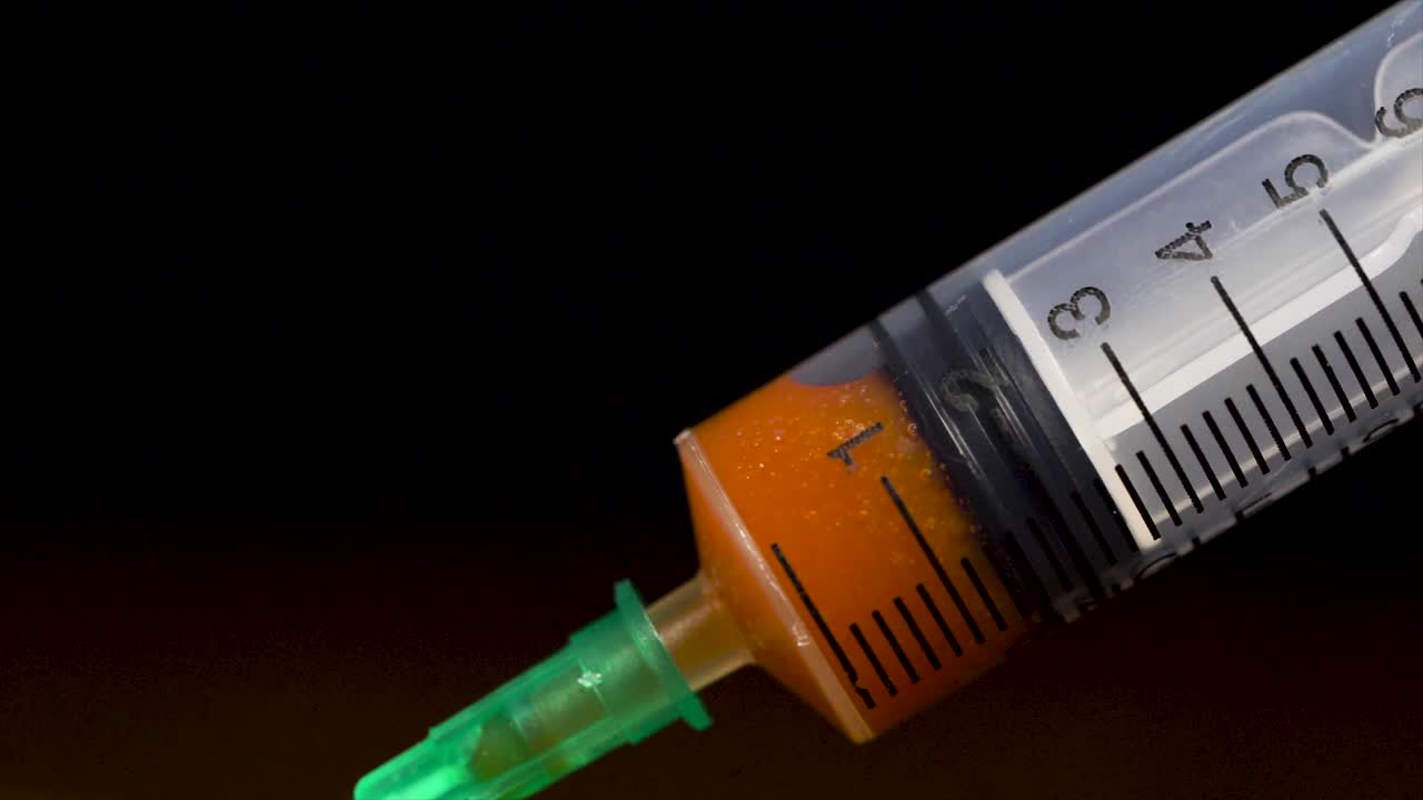 una jeringa llena de líquido naranja