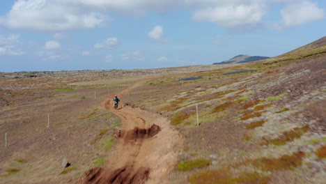 Vista-Aérea-Siguiendo-Al-Hombre-Haciendo-Motocross-Sobre-Una-Colina-En-Islandia.-Vista-De-Drones-De-Ciclistas-Montando-En-Camino-De-Tierra-Entre-Montañas