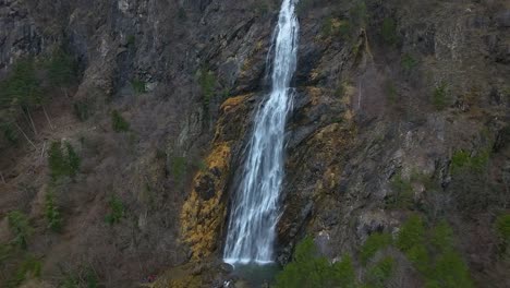 Luftaufnahme-Eines-Gewaltigen-Wasserfalls,-Der-Eine-Steile,-Felsige-Klippe-Hinabstürzt,-Umgeben-Von-üppigem-Grün