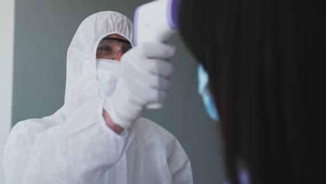 trabajador de la salud con ropa de protección midiendo la temperatura de una mujer