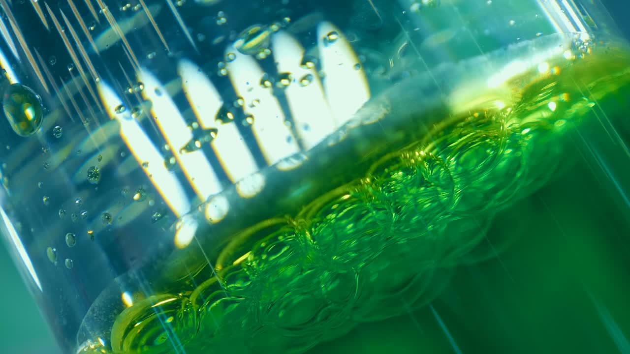 녹색 기름의 물방울은 천천히 물의 바닥으로 떨어집니다.