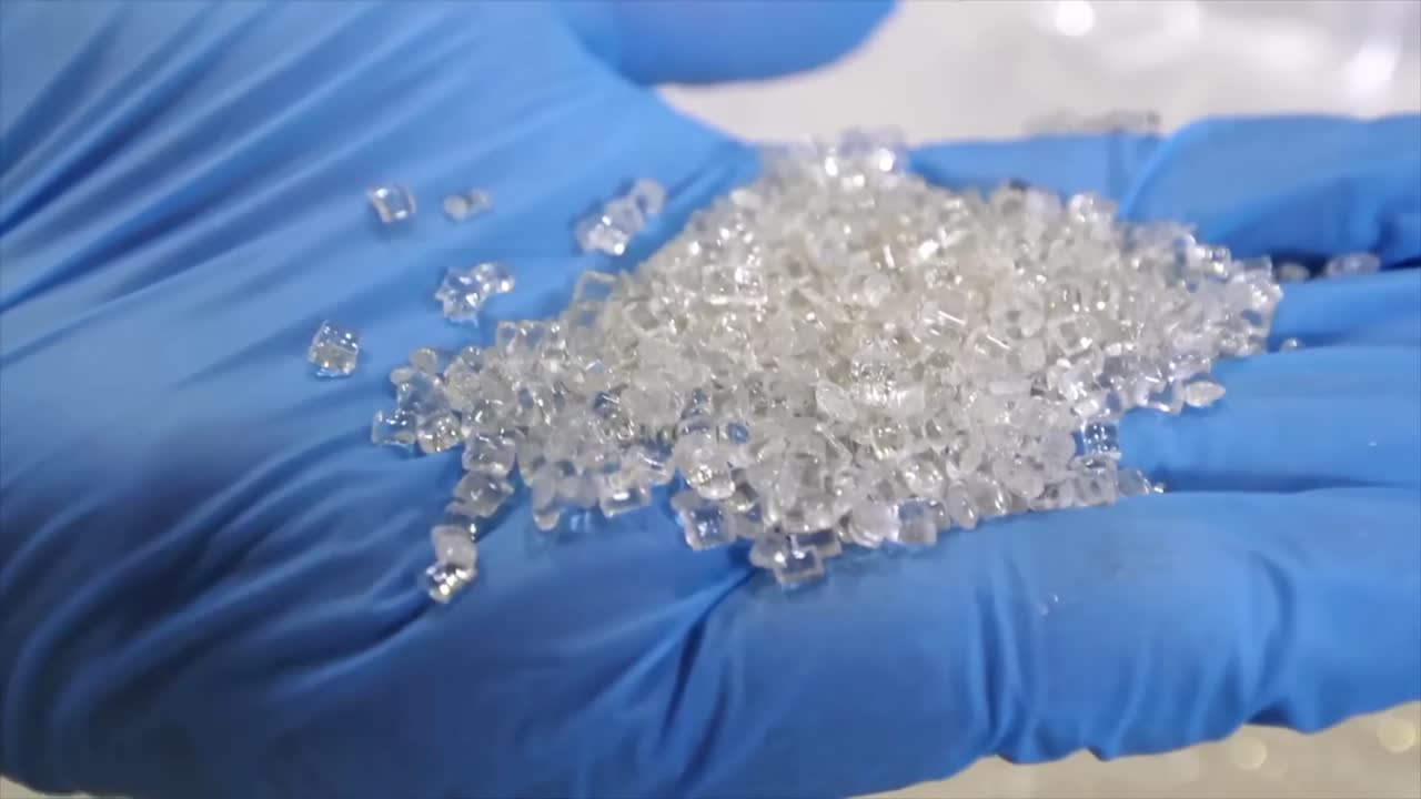 A handful of propylene or polyethylene pellets in a blue gloved hand.