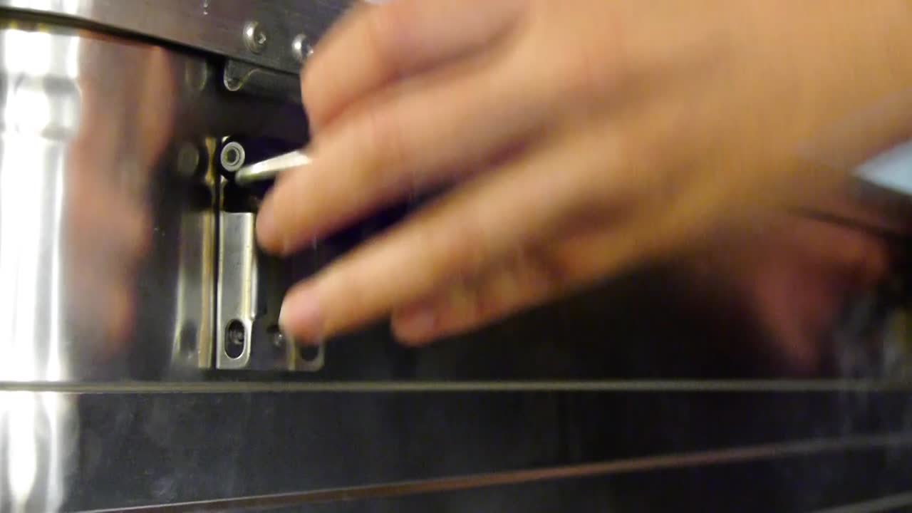 A hand opens the closure of a metal box and opens it