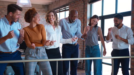 Business-Team-Celebrating-In-Meeting-In-Multi-Cultural-Office-With-Colleagues-Dancing-And-Having-Fun