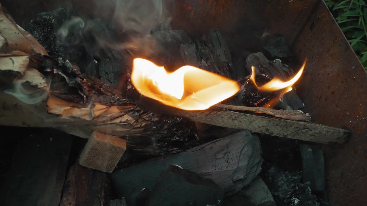 Nærbillede af flammer, der antænder trækul og træ til grill