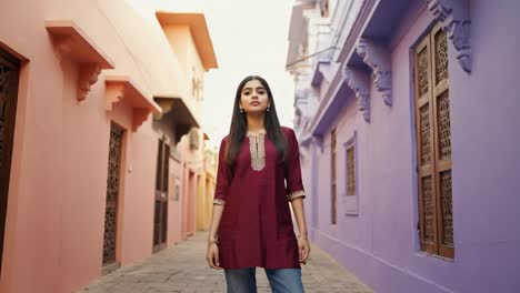 stylish young female model wearing traditional indian kurta, confidently posing against vibrant colorful walls of urban alley during sunny daytime