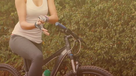 manchas de luz contra la sección media de la mujer con guantes antes de montar su bicicleta