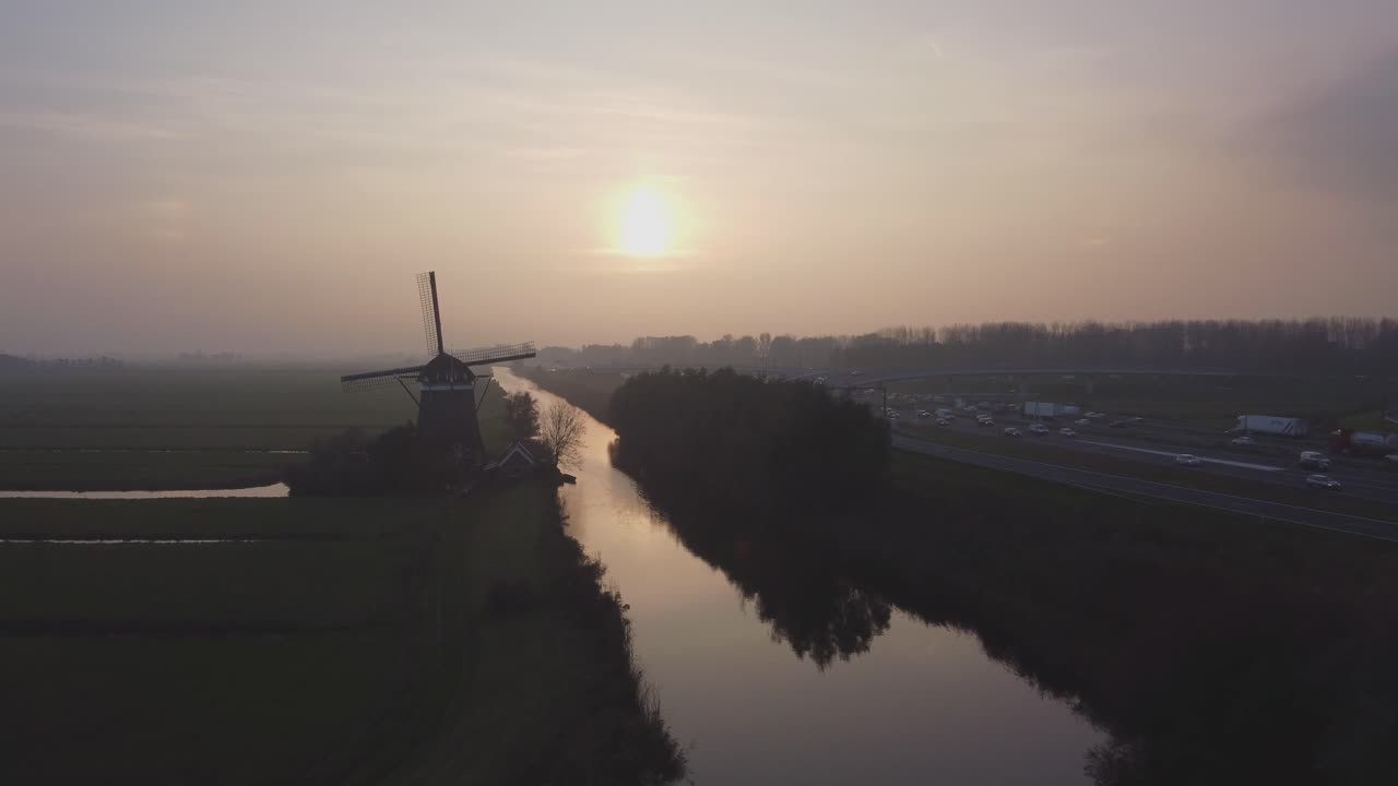 Windmill sunset, calm and still, while transport drives past that old mill