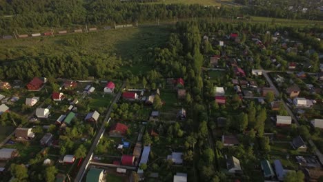 Flying-over-village-houses-and-moving-cargo-train