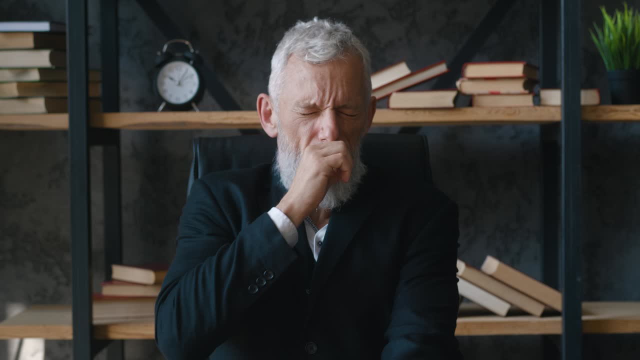 충격에 빠진 성숙한 사업가는 카메라를 바라보고 끔찍한 소식에 놀란 손으로 얼굴을 습니다. 무서운 사업가는 현대적인 사무실에서 실내에 앉아있는 동안 나쁜 소식에 반응합니다.