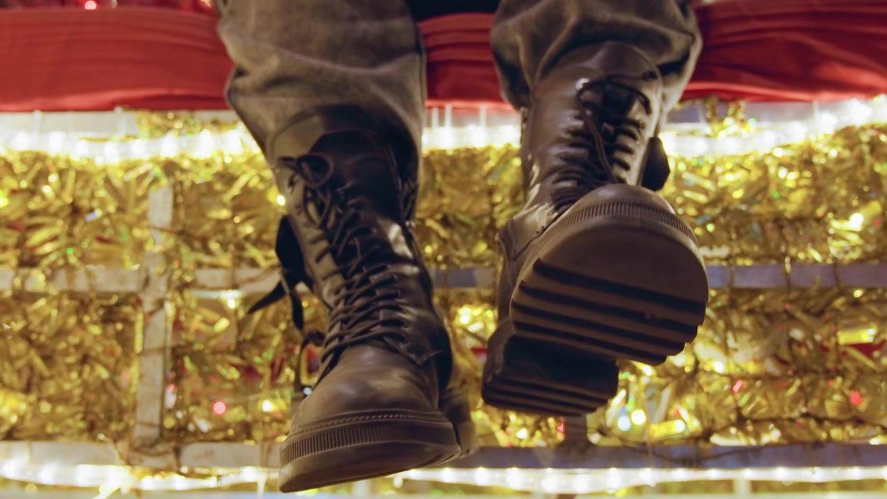 Entschlossener Stadtspaziergang. Robuste Lederstiefel in Bewegung. Kühne Reise durch Stadtlichter mit selbstbewusstem Schuhwerk. Energische Bewegung über leuchtende Weihnachtsdekorationen in robusten Lederschuhen.