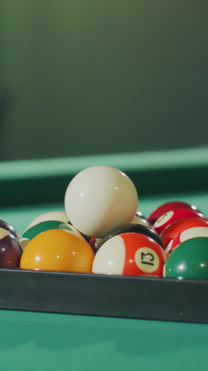 Primo piano di colorate palle da biliardo disposte ordinatamente nel triangolo su un tavolo da biliardo verde, con colori vivaci e illuminazione soffusa che mettono in risalto la loro texture e la superficie liscia in una sala giochi accogliente