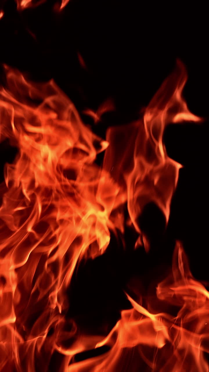 Lingue di fiamma rosse che si muovono nell'oscurità. Fiammata calda isolata con scintille che volano in alto. Primo piano. Video verticale
