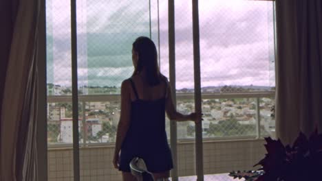 silhouette of brunette woman opening balcony sliding glass door at home, admiring view of neighborhood