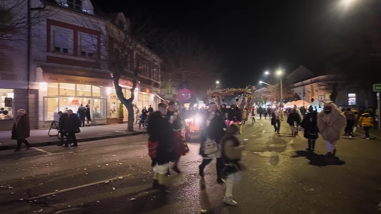 Loud and reed decorated chariot rushes through the main street of Mohacs in the evening as part of the Busó-walking event in Hungary.