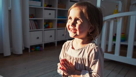 una niña orando en un dormitorio soleado