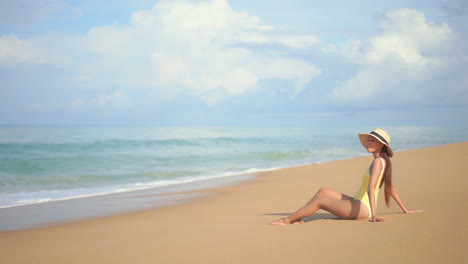 Eine-Hübsche-Junge-Fitte-Frau-Sitzt-An-Einem-Sandstrand-In-Südostasien-Und-Genießt-Die-Sonne,-Während-Die-Wellen-Hereinrollen